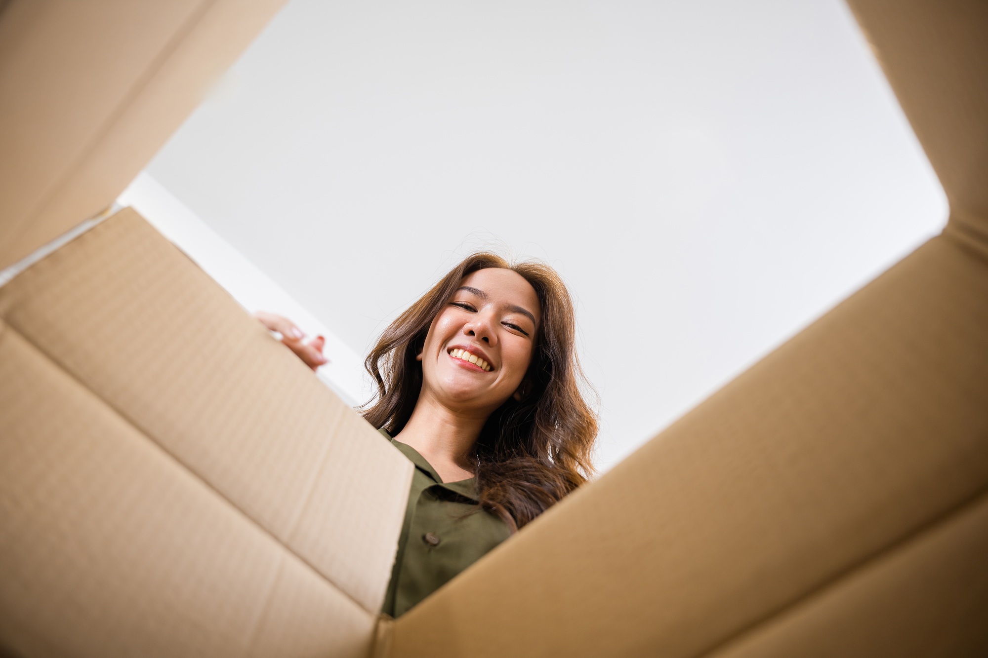 Happy Asian young woman opening carton box from internet store order shopping online